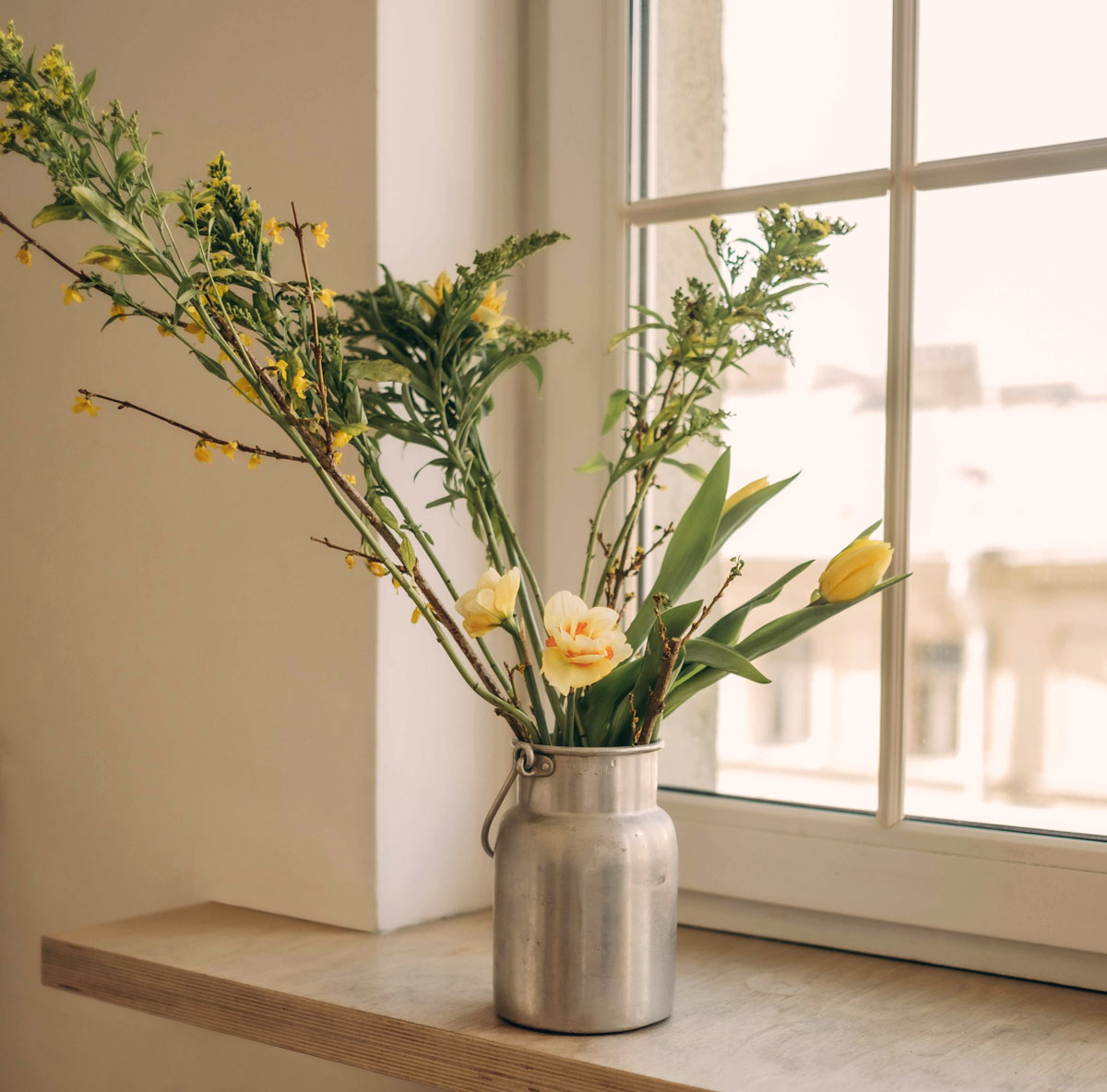 Vase of yellow flowers on a window sill